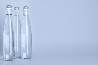 Glass bottles with water on white background, space for text