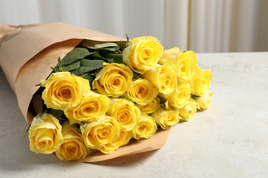 Photo of Beautiful bouquet of yellow roses on light grey table, space for text