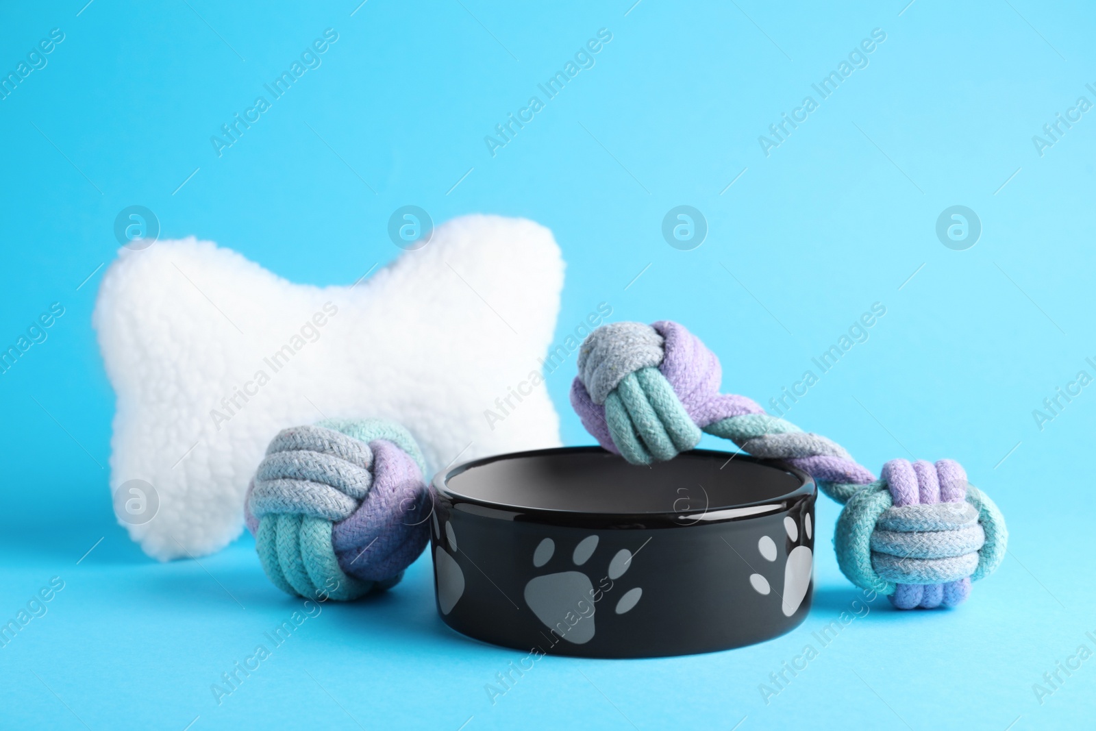 Photo of Feeding bowl and toys for pet on light blue  background