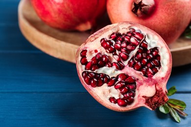 Delicious ripe pomegranates on blue wooden table, closeup