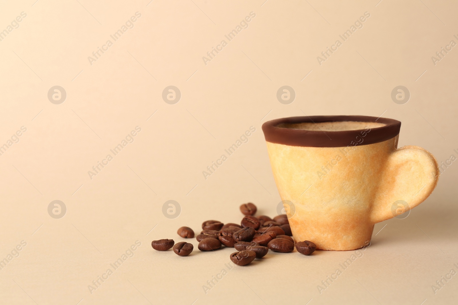 Photo of Delicious edible biscuit cup with espresso and coffee beans on beige background. Space for text