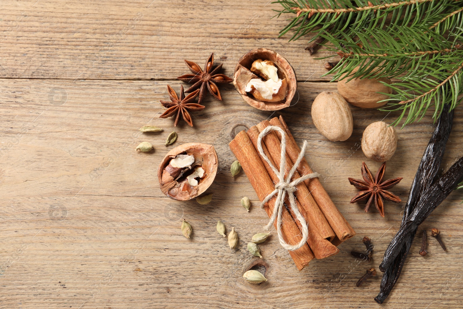 Photo of Different spices, nuts and fir branches on wooden table, flat lay. Space for text