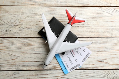 Photo of Toy airplane and passport with tickets on white wooden background, flat lay