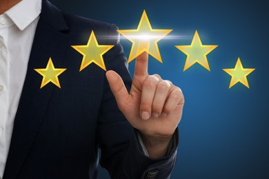 Image of Quality evaluation. Businessman touching virtual golden star on blue background, closeup