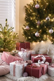 Gift boxes under small and big Christmas trees indoors