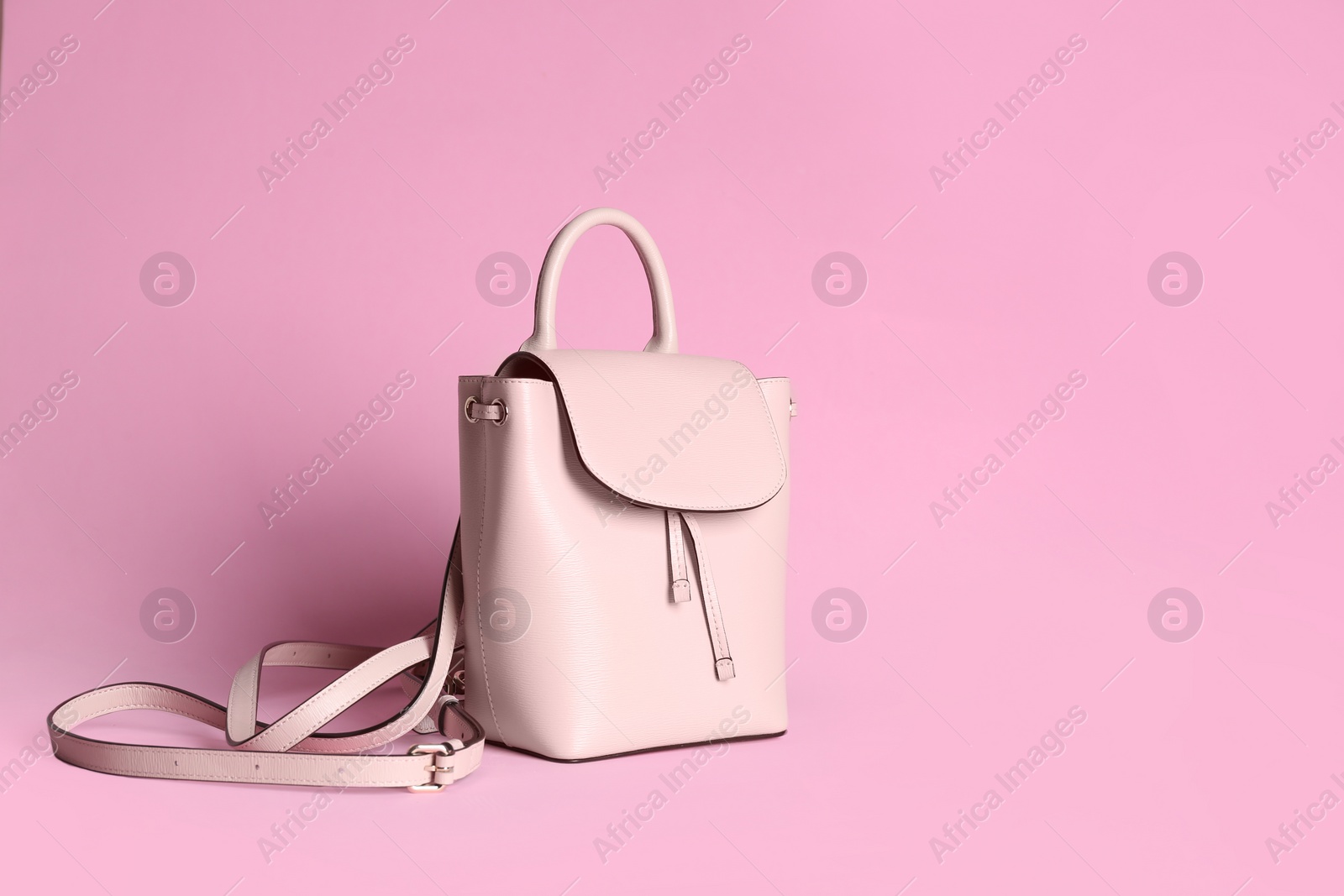 Photo of Stylish woman's backpack on light pink background. Space for text