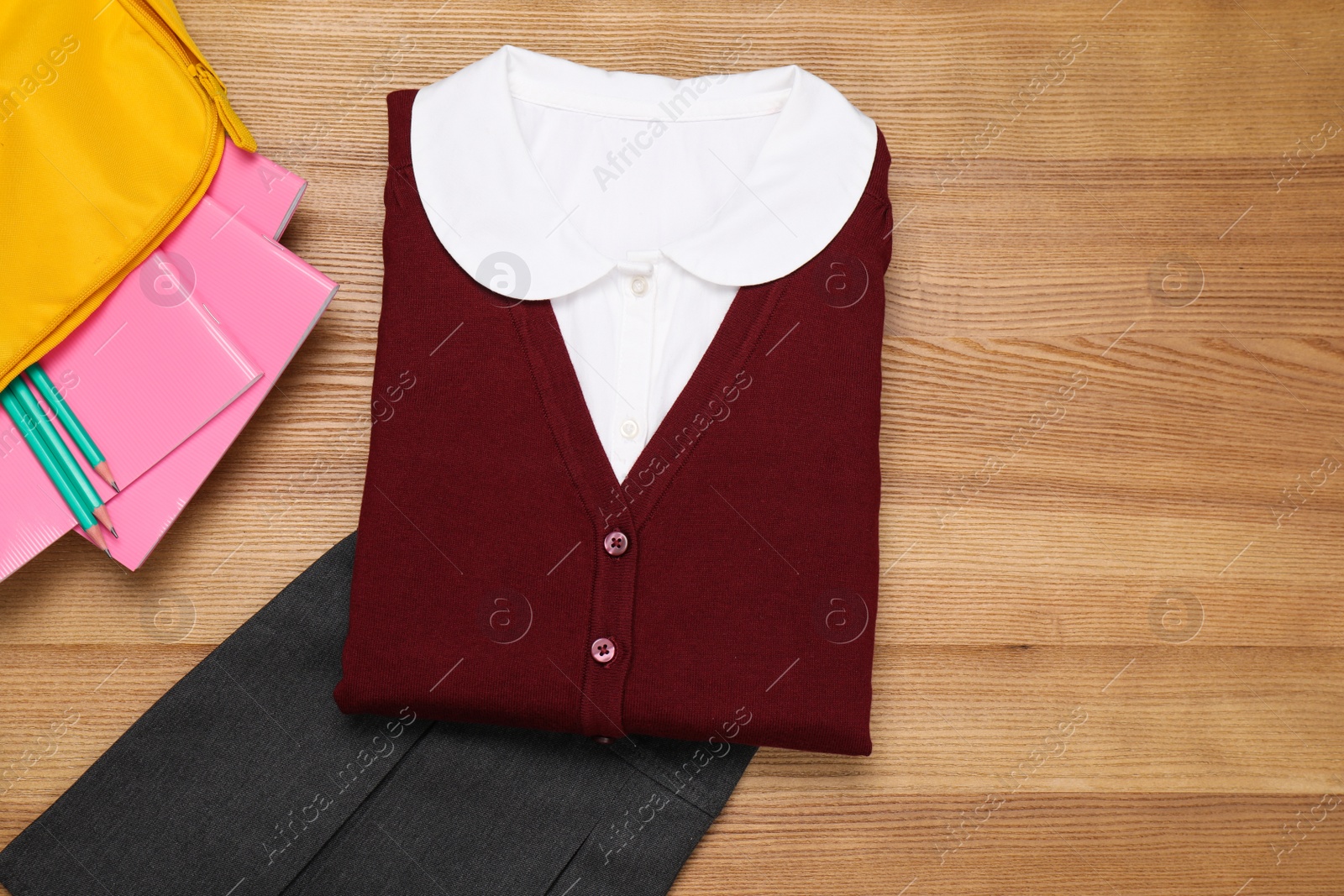 Photo of School uniform for girl and stationery on wooden background