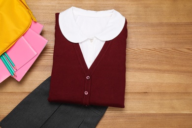 Photo of School uniform for girl and stationery on wooden background