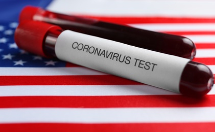 Test tubes with blood samples on American flag, closeup. Coronavirus pandemic in USA