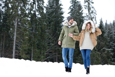 Couple near conifer forest on snowy day, space for text. Winter vacation