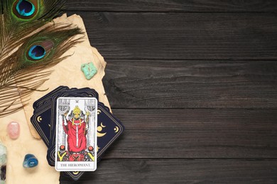The Hierophant with other tarot cards near peacock feathers and gemstones on black wooden table, flat lay. Space for text