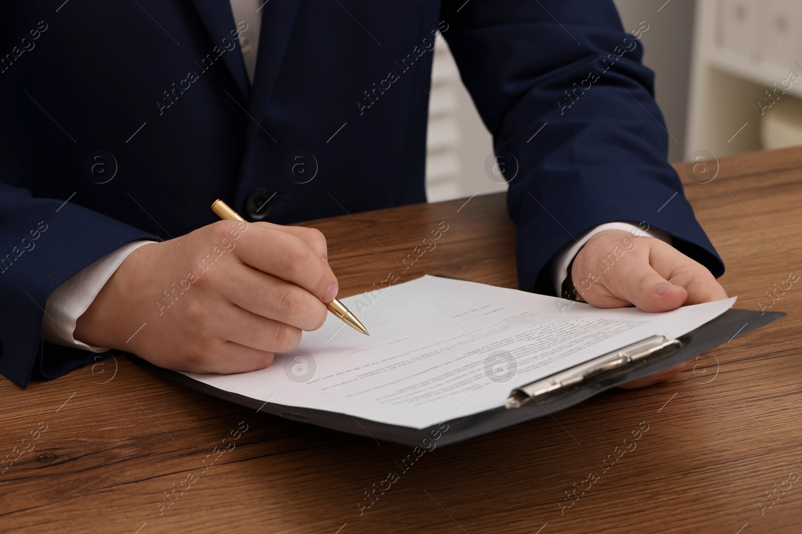 Photo of Man signing document at wooden table, closeup