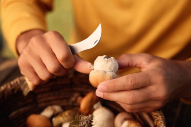 Photo of Man cutting mushroom with knife over basket, closeup