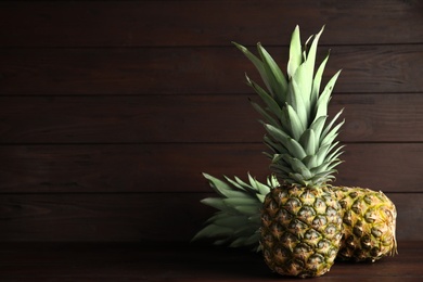 Photo of Fresh ripe juicy pineapples on wooden table. Space for text