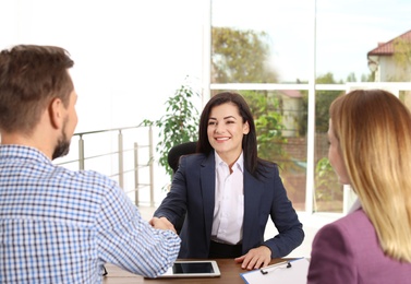 Human resources manager shaking hands with applicant during job interview in office