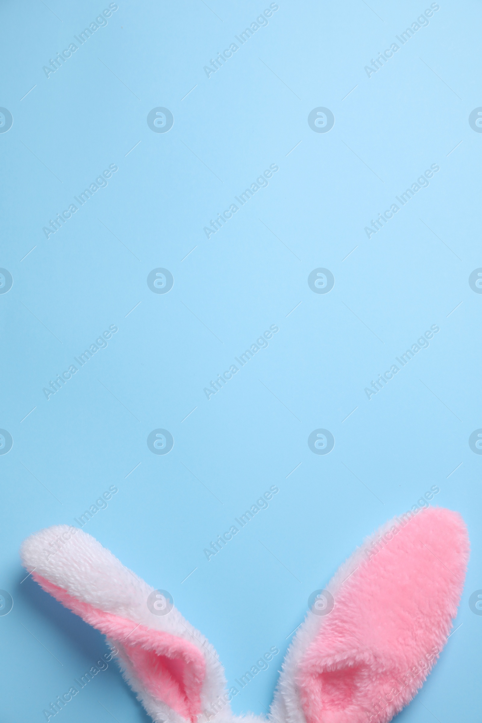 Photo of Decorative bunny ears and space for text on light blue background, flat lay. Easter holiday