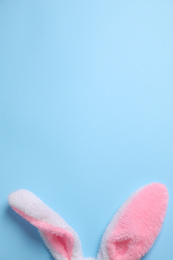 Decorative bunny ears and space for text on light blue background, flat lay. Easter holiday