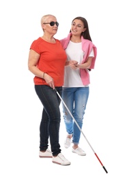 Young woman helping blind person with long cane on white background