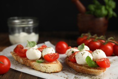 Delicious sandwiches with mozzarella, fresh tomatoes and basil on wooden table. Space for text