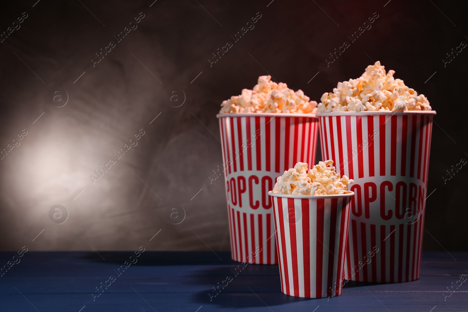 Photo of Delicious popcorn on blue wooden table. Space for text