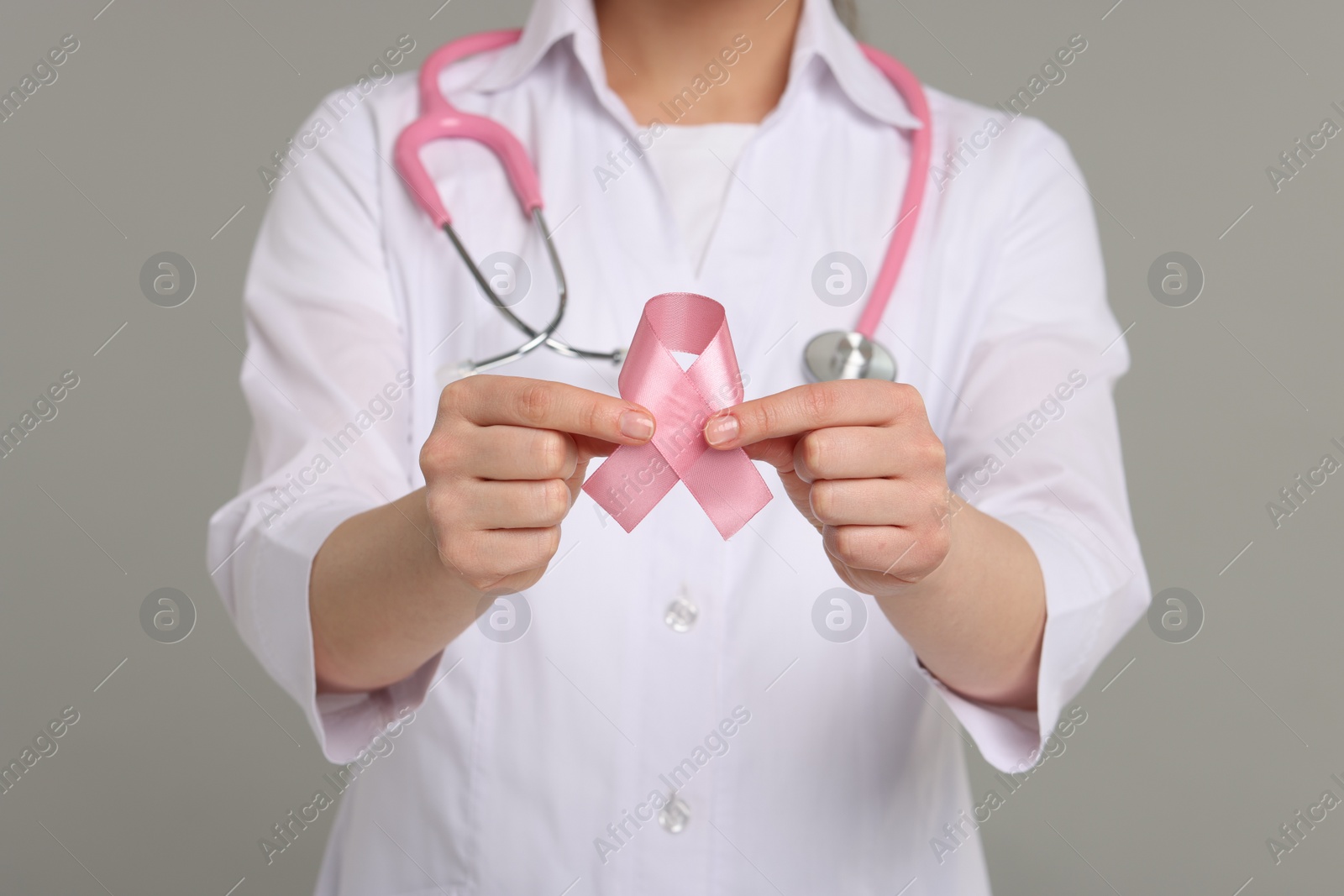 Photo of Mammologist with pink ribbon on gray background, closeup. Breast cancer awareness