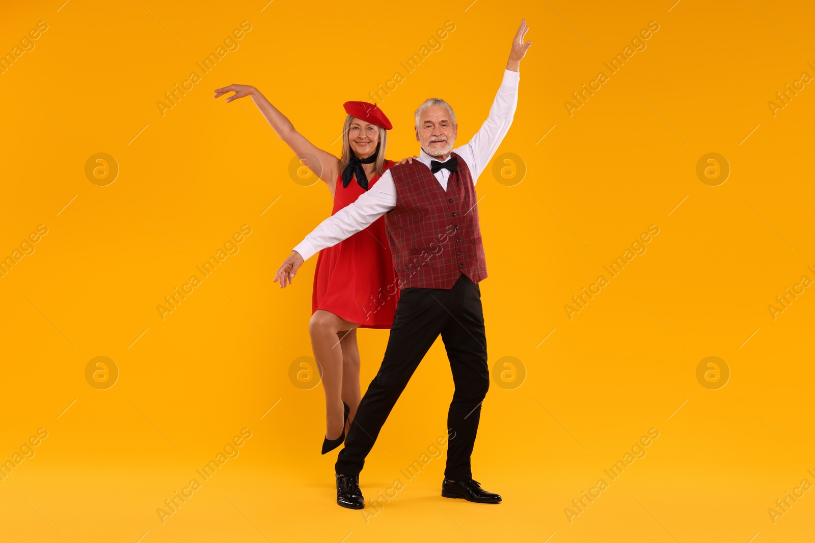 Photo of Senior couple dancing together on orange background