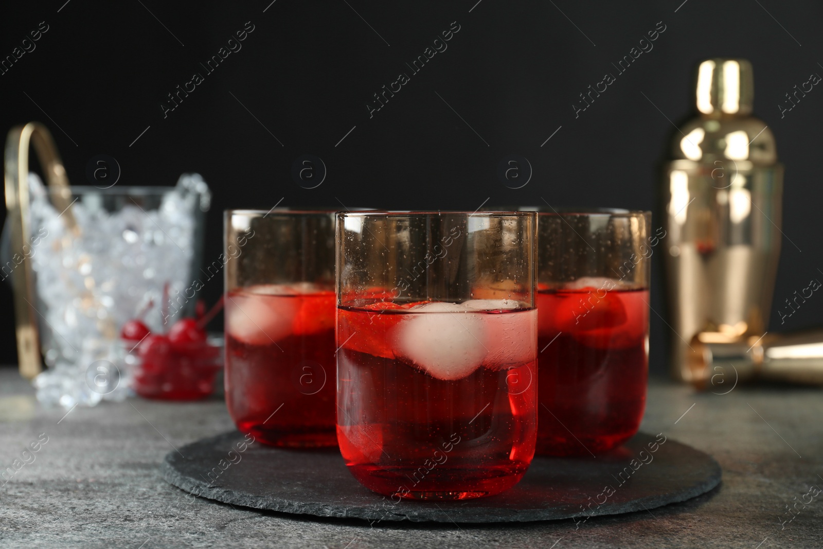 Photo of Delicious cocktails with strawberries and ice balls on grey table