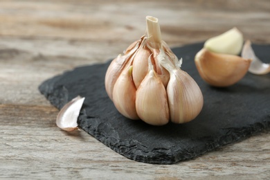 Photo of Slate plate with garlic on wooden background