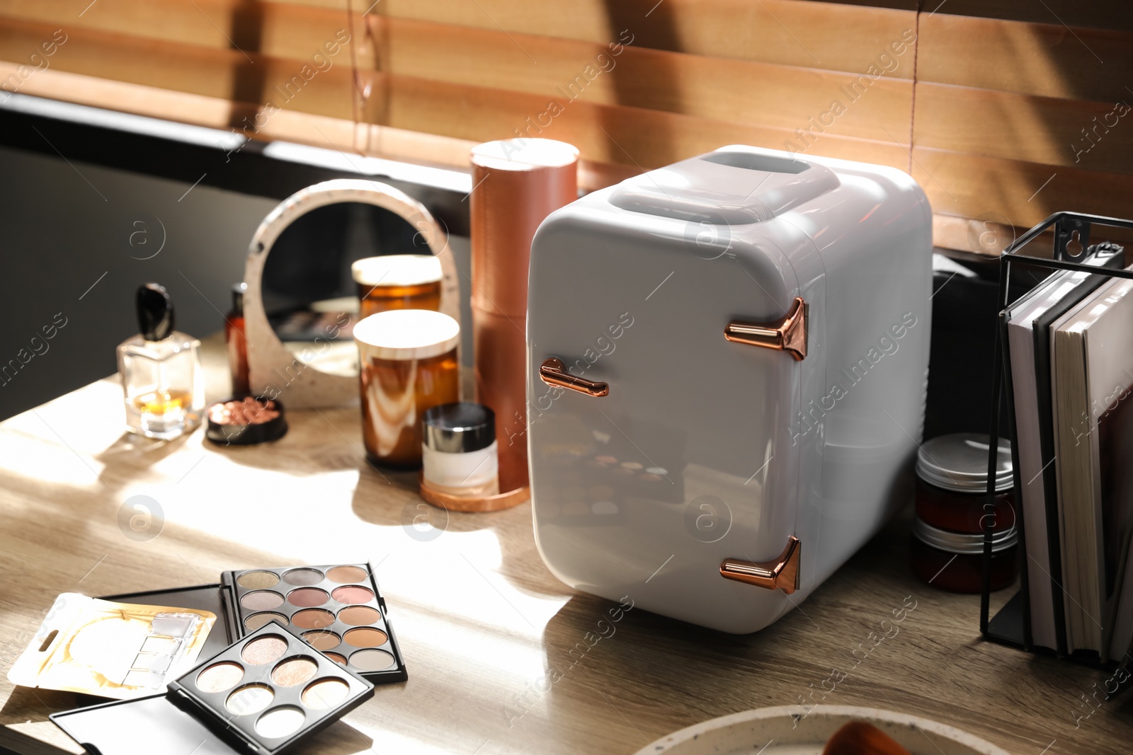 Photo of Mini fridge for cosmetic products on wooden vanity table