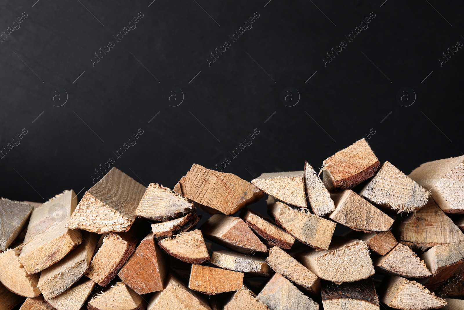 Photo of Cut firewood on black background. Space for text