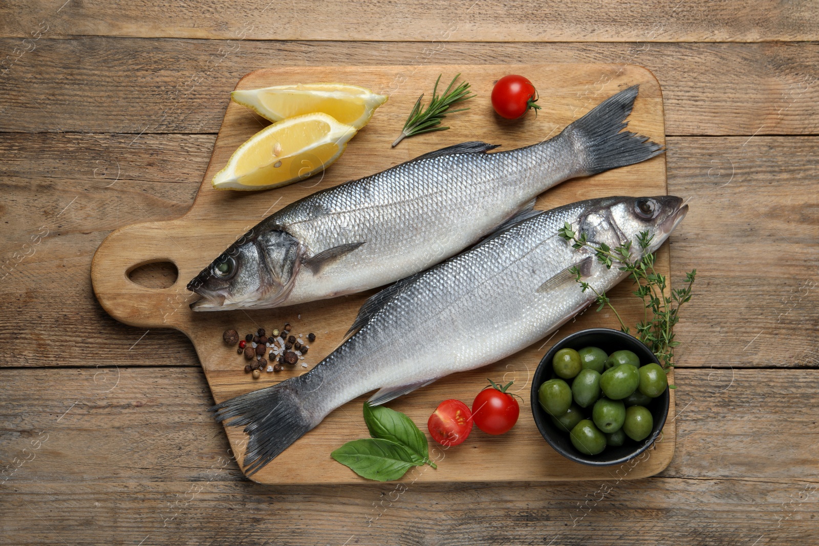 Photo of Sea bass fish and ingredients on wooden table, top view