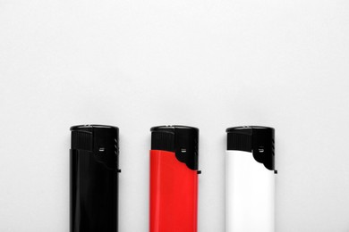 Photo of Stylish small pocket lighters on white background, flat lay. Space for text