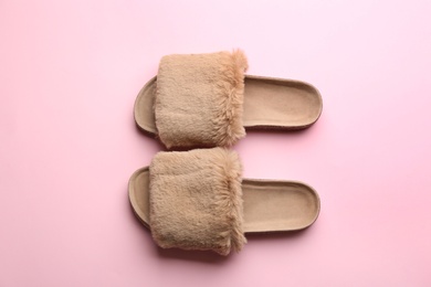 Pair of soft slippers on light pink background, flat lay