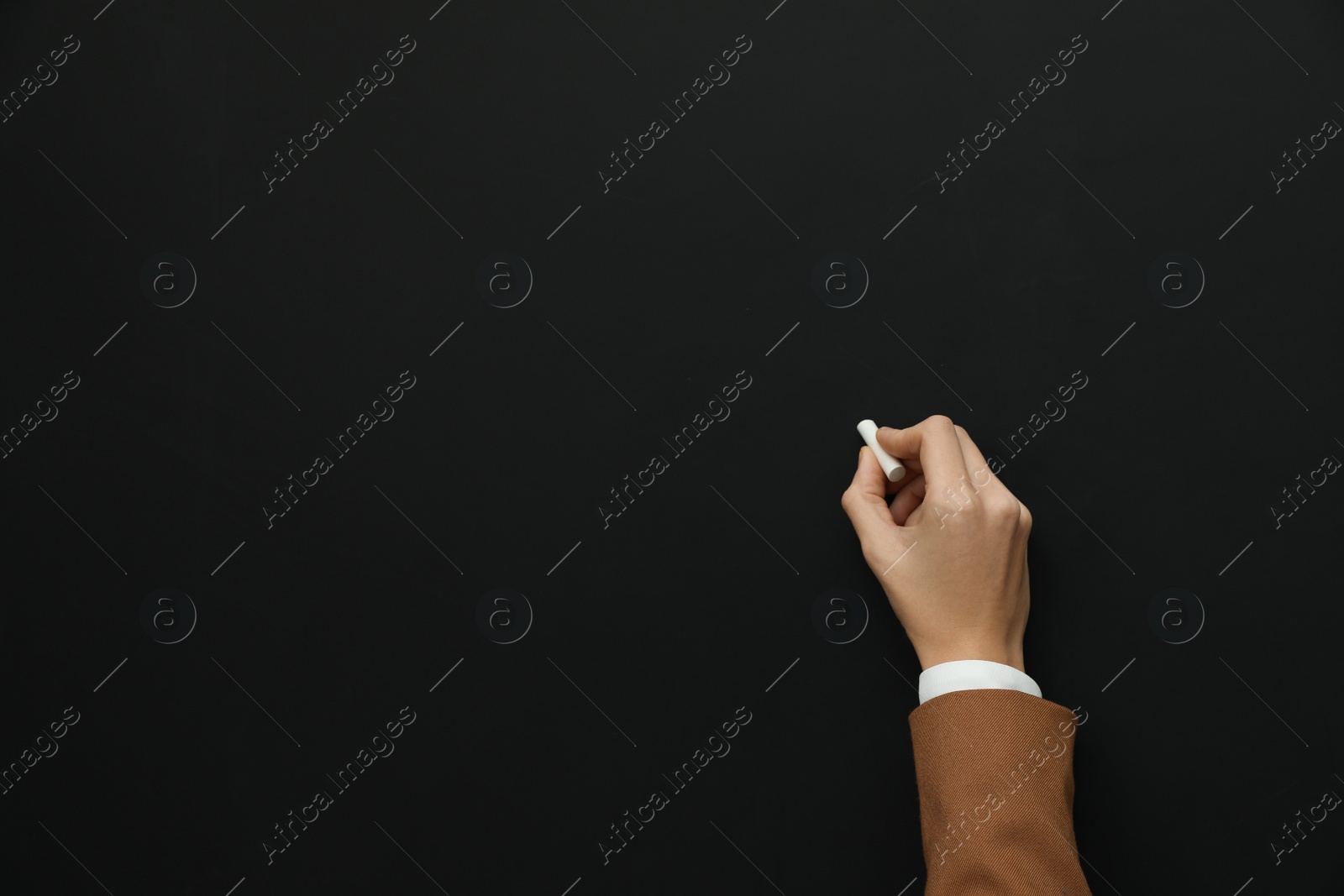 Photo of Woman with white chalk near blackboard, closeup. Space for text