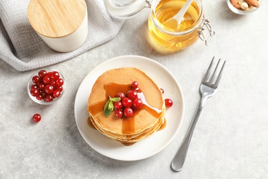 Photo of Stack of tasty pancakes with berries and syrup on table, top view