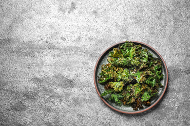 Tasty baked kale chips on grey table, top view. Space for text