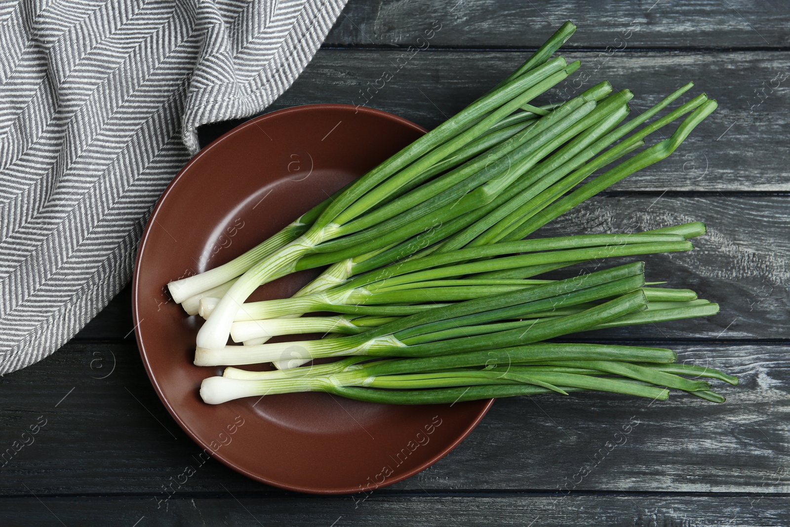 Photo of Fresh green spring onions on black wooden table, flat lay