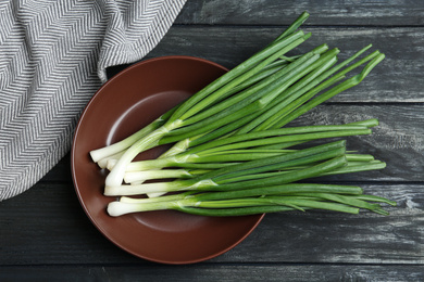 Fresh green spring onions on black wooden table, flat lay