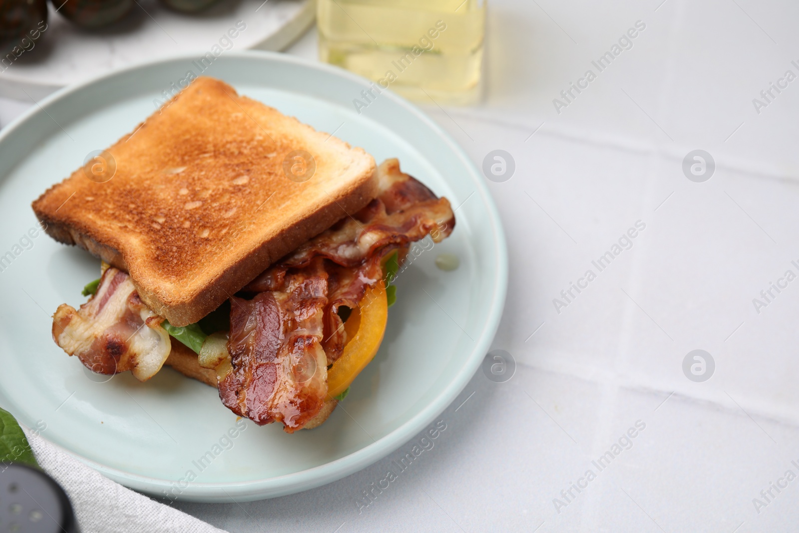 Photo of Tasty sandwich with bacon and bell pepper on white tiled table, space for text