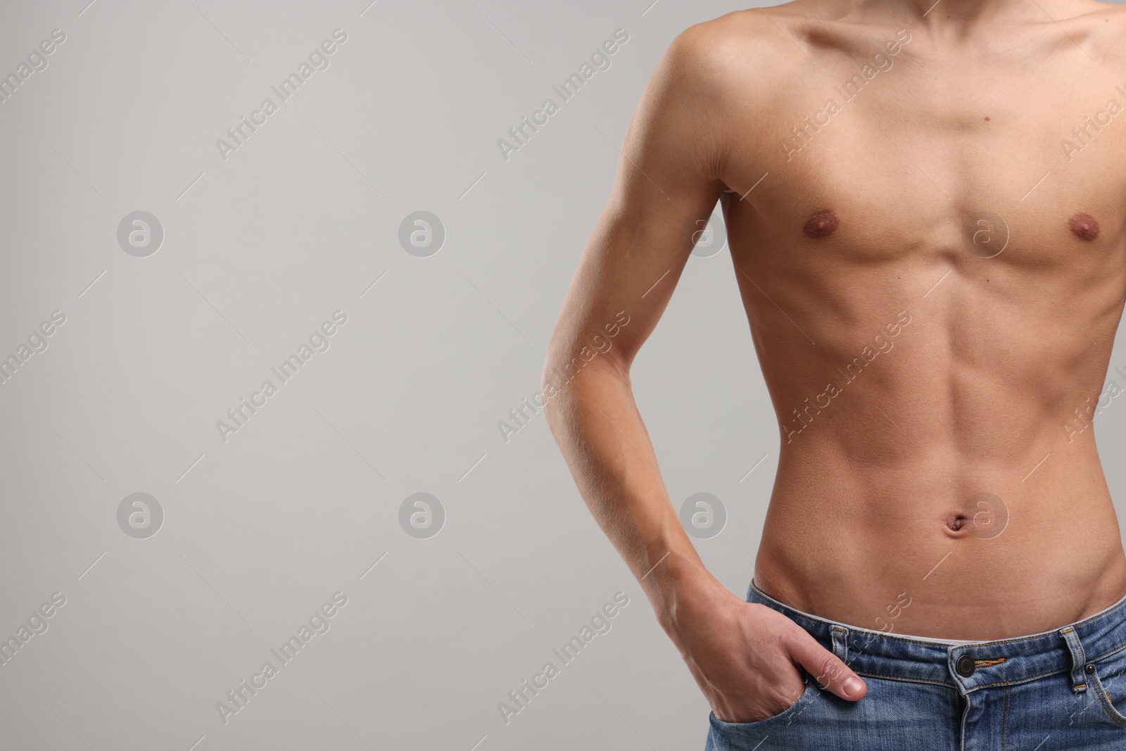 Photo of Shirtless man with slim body on grey background, closeup. Space for text