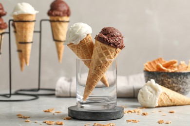 Photo of Tasty ice cream scoops in waffle cones on grey marble table, closeup
