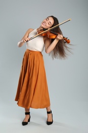 Photo of Beautiful woman playing violin on grey background