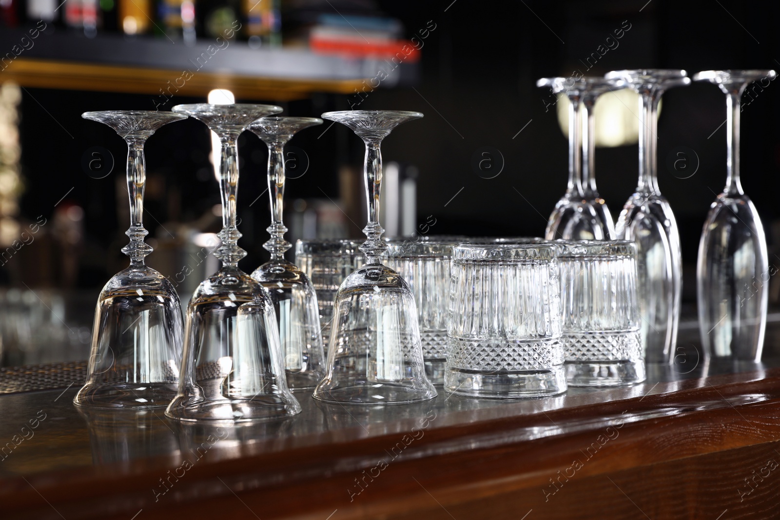 Photo of Different empty clean glasses on counter in bar