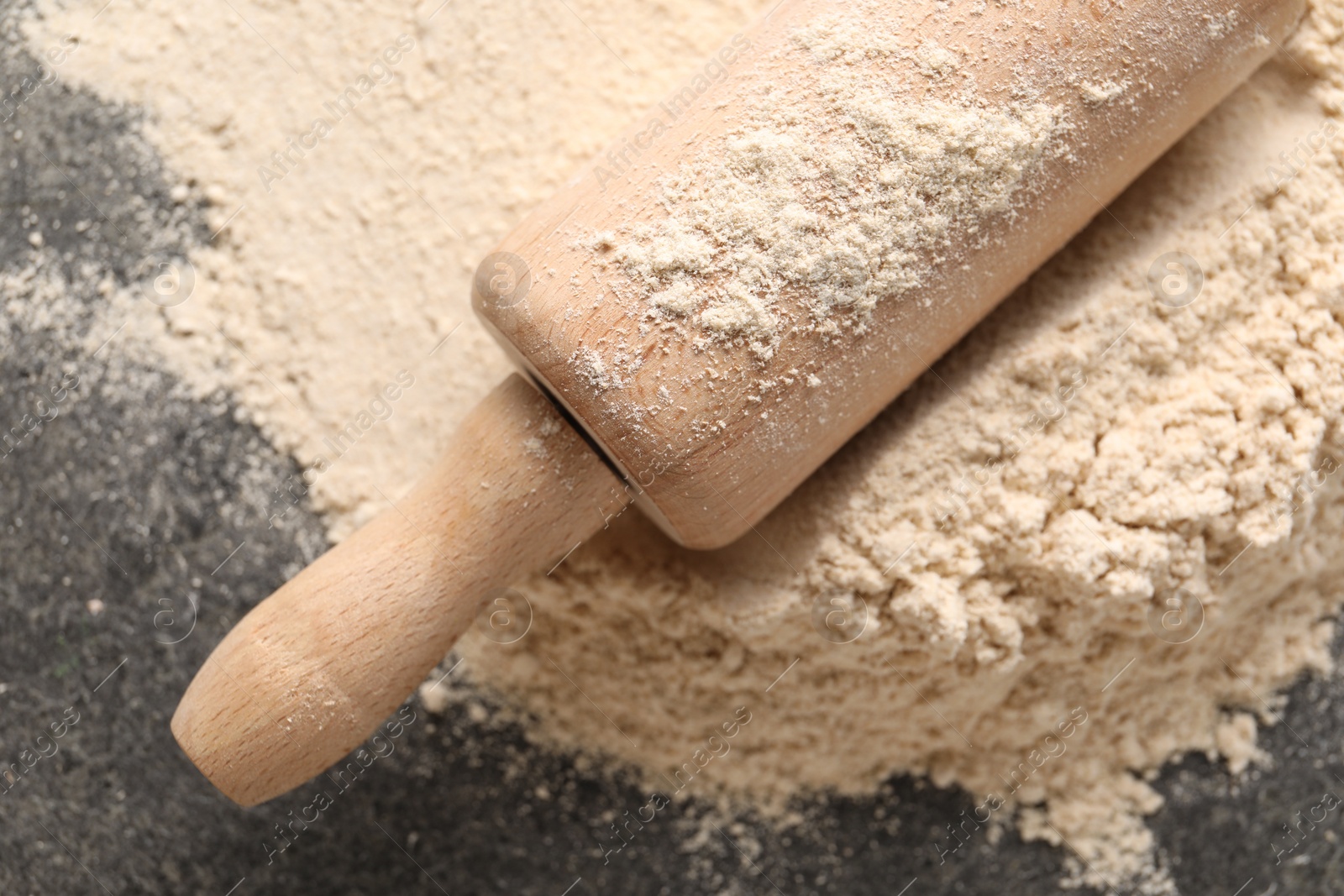 Photo of Scattered flour and rolling pin on grey textured table, top view