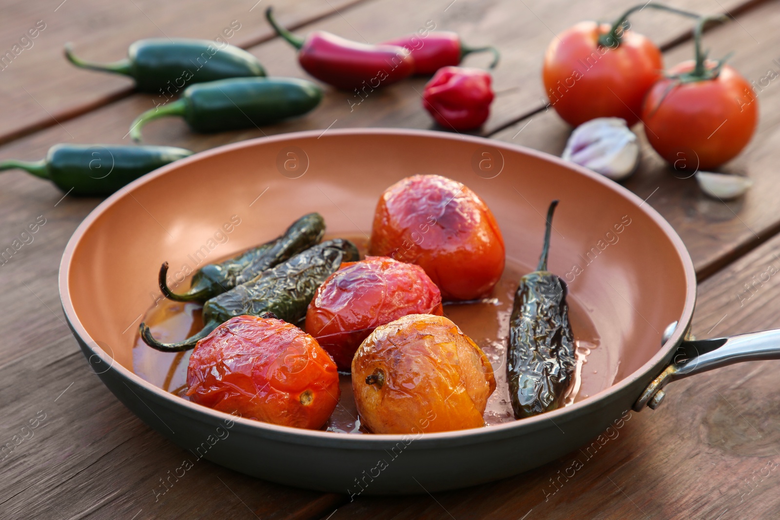 Photo of Frying pan with ingredients for salsa sauce on wooden table