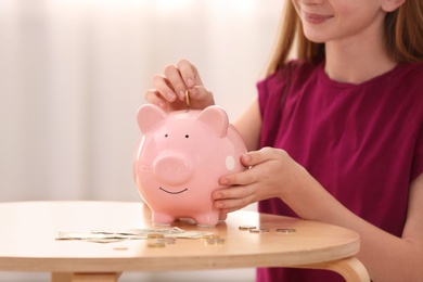 Photo of Teen girl with piggy bank and money at home, closeup