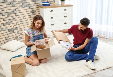 Photo of Young couple opening parcels on floor at home