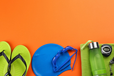 Flat lay composition with swimming accessories on orange background. Space for text