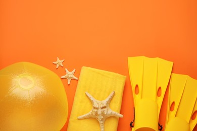 Flat lay composition with ball and beach objects on orange background, space for text