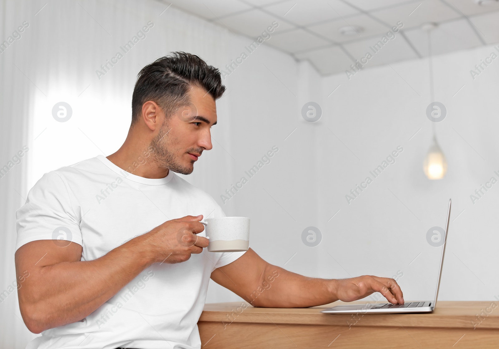 Photo of Portrait of handsome young man with laptop at home